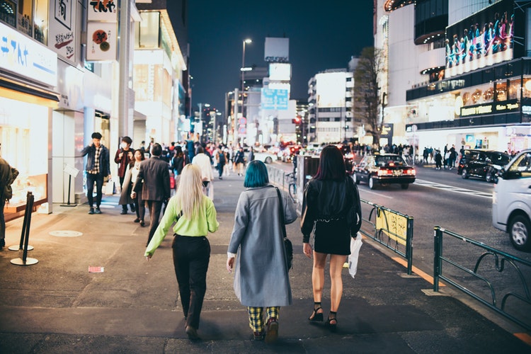 Tre ragazze di spalle che camminano in una metropoli